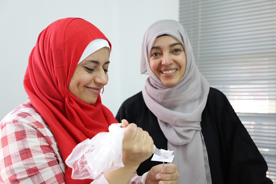 Etemad (right), a Yemeni refugee taking part in the LEAP programme, learns how to make sugar flowers for cake decorating. Photo: UN Women/Nada Ismail